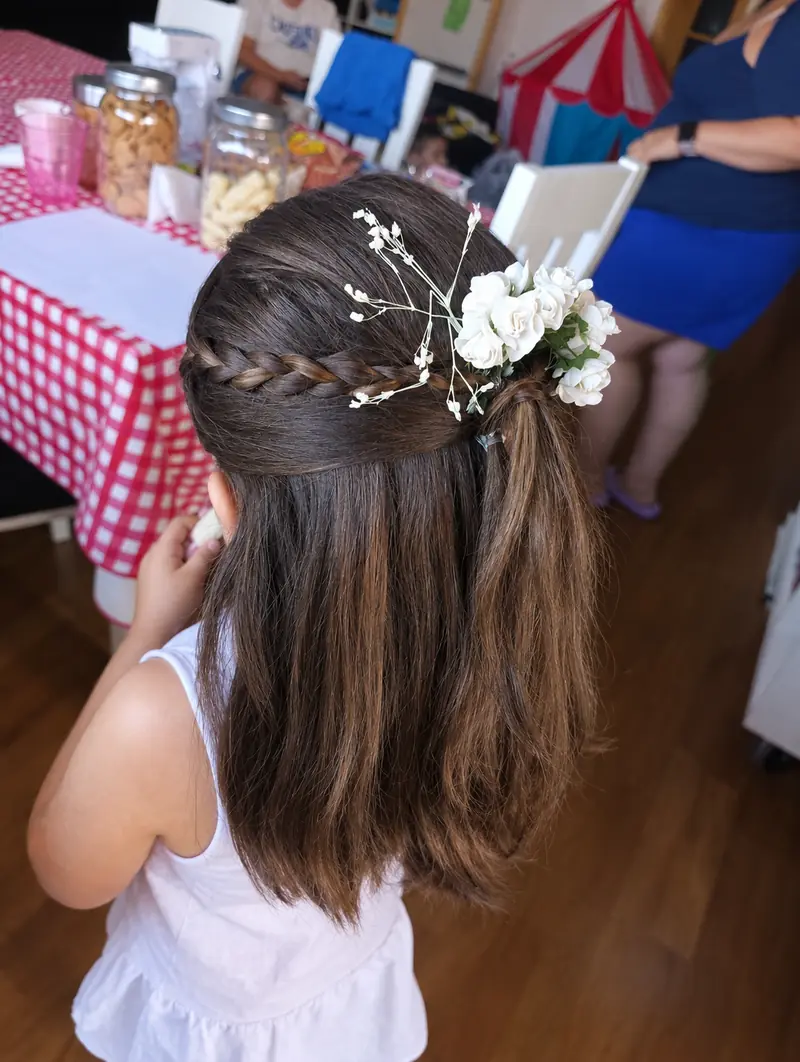 Semirrecogido de niña con trenza y flores blancas